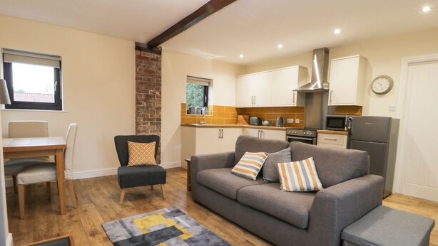 A compact living space with a kitchenette, a dining area, and a sofa set.