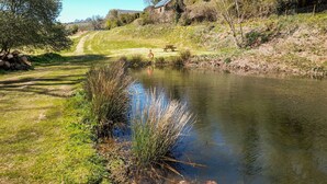 A riverside path with a picnic table and a house in the background.