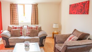 A living room with two sofas, a coffee table, a lamp, and a painting on the wall. - Stonecroft Lodge (Belper)