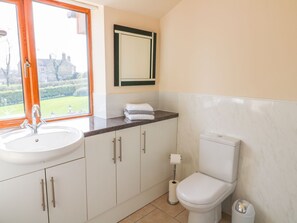 Un baño con lavamanos, inodoro y ventana con vistas a un jardín.