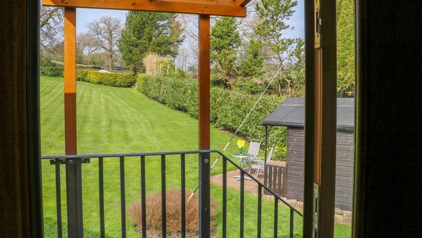 A view from a covered porch with a lawn and a small shed in the background. - Stonecroft Lodge (Belper)