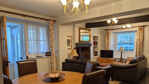 Una sala de estar con una mesa redonda de madera, sofás de cuero, una chimenea, un televisor y una estantería.