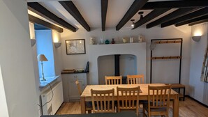 Un comedor con una mesa y sillas de madera, un mapa en la pared y una estufa negra.