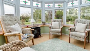 A conservatory with two armchairs, a table, and a lamp. - Grazeland Cottage (Bridport)