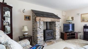 A cozy living room with a stone fireplace, a television, and comfortable seating.