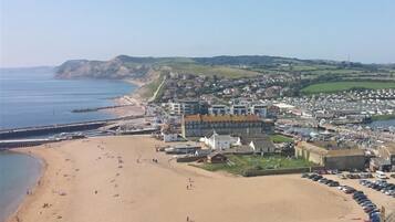 A coastal town with a sandy beach, a pier, and a mix of residential and commercial buildings.