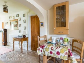Un comedor con una mesa dispuesta para el té, un mueble de madera encima y cuadros enmarcados en la pared.