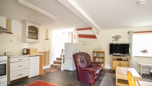 Ett kompakt bostadsutrymme med kök, matplats och en sittgrupp med en fåtölj klädd i läder.