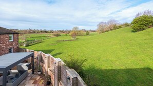 Ein Backsteinhaus mit Terrasse, einer grünen Wiese und einem Holzzaun.