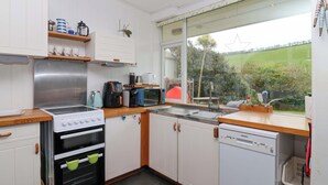 Une cuisine moderne avec des meubles blancs, une cuisinière, un four à micro-ondes et un lave-vaisselle.
