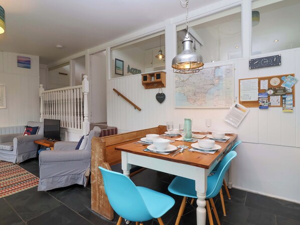 A dining area with a wooden table set for four, blue chairs, and a hanging light fixture.