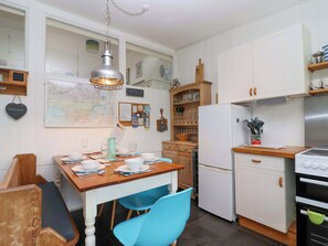 A kitchen with white cabinets, a wooden table, blue chairs, a refrigerator, and an oven.