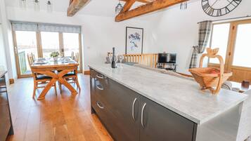 A spacious kitchen with wooden beams, a large island, and a dining area with a view.