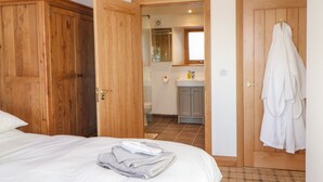A bedroom with a bed, a bathroom with a sink and mirror, and a wardrobe. - Apple Tree Cottage (Appleby-in-Westmorland)