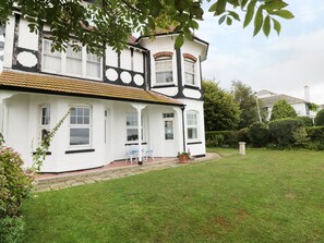 A traditional two-story house with a white exterior and black trim, a tiled roof, and a well-maintained lawn.