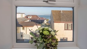Une fenêtre donnant sur des maisons et la mer.