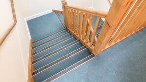 A wooden staircase with a blue carpeted landing and a white wall. - 5 Old Laundry Mews (Carnforth)
