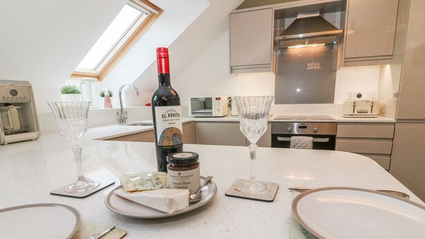 A modern kitchen with a dining area set for a meal. - 5 Old Laundry Mews (Carnforth)