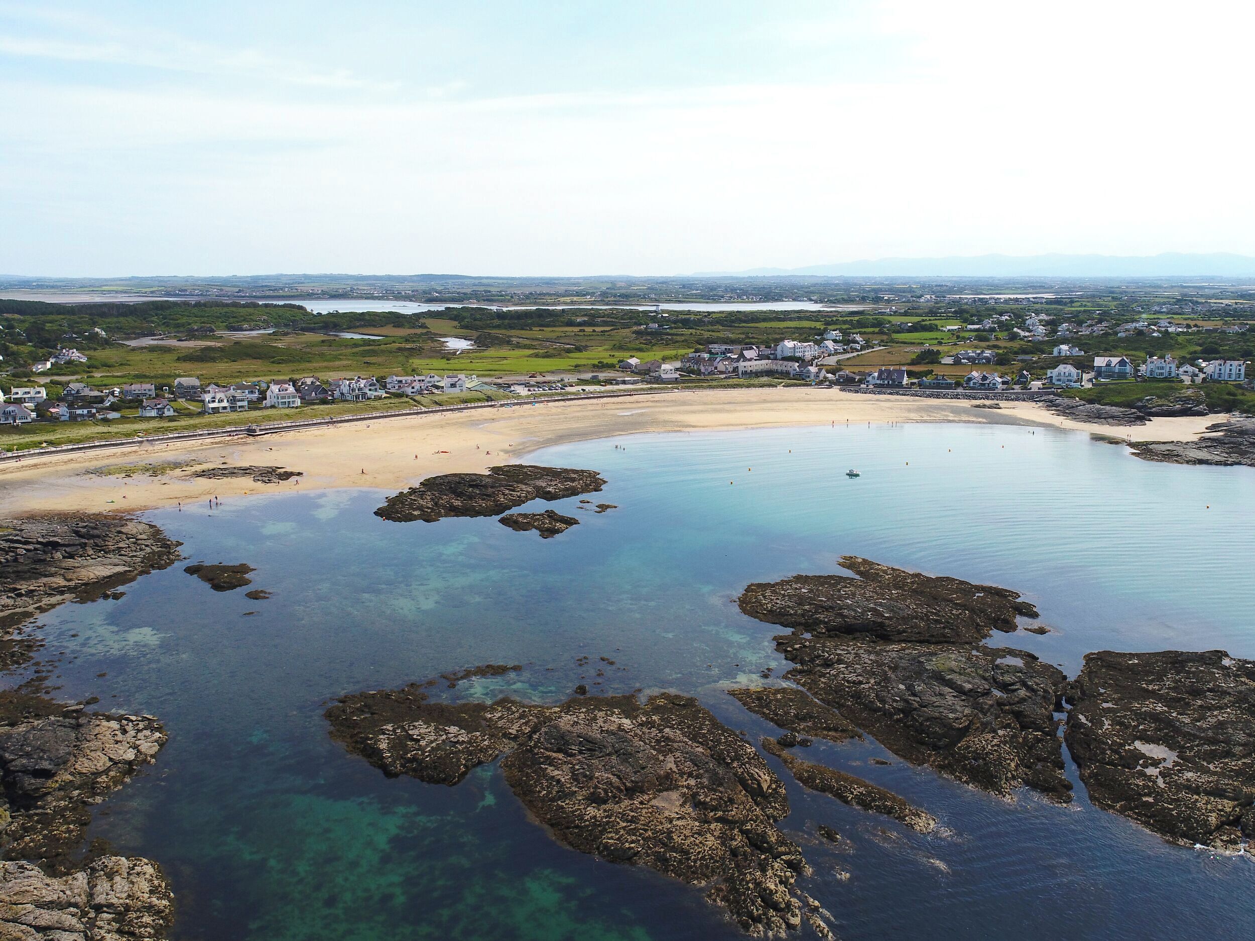 A coastal area with a sandy beach, clear waters, and rocky outcrops.