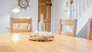 A wooden dining table with a bottle and a pile of stones on it. - Curragho (Holyhead)