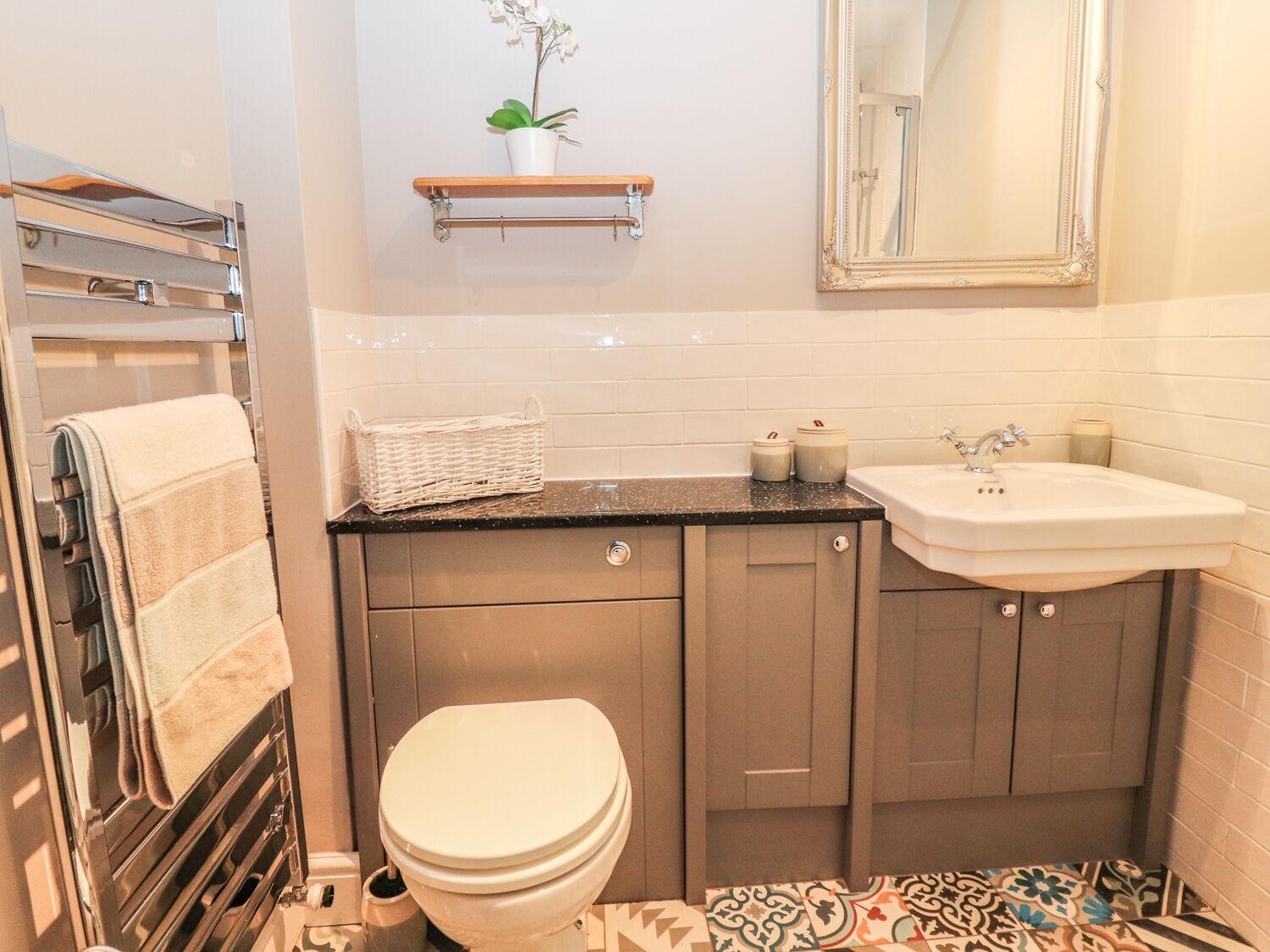 Un baño con inodoro, lavamanos y perchero para toallas.
