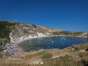 Une zone côtière avec une plage, des bateaux et un ciel dégagé.