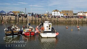 Un port avec des bateaux amarrés, un mur de pierre et des bâtiments en arrière-plan.