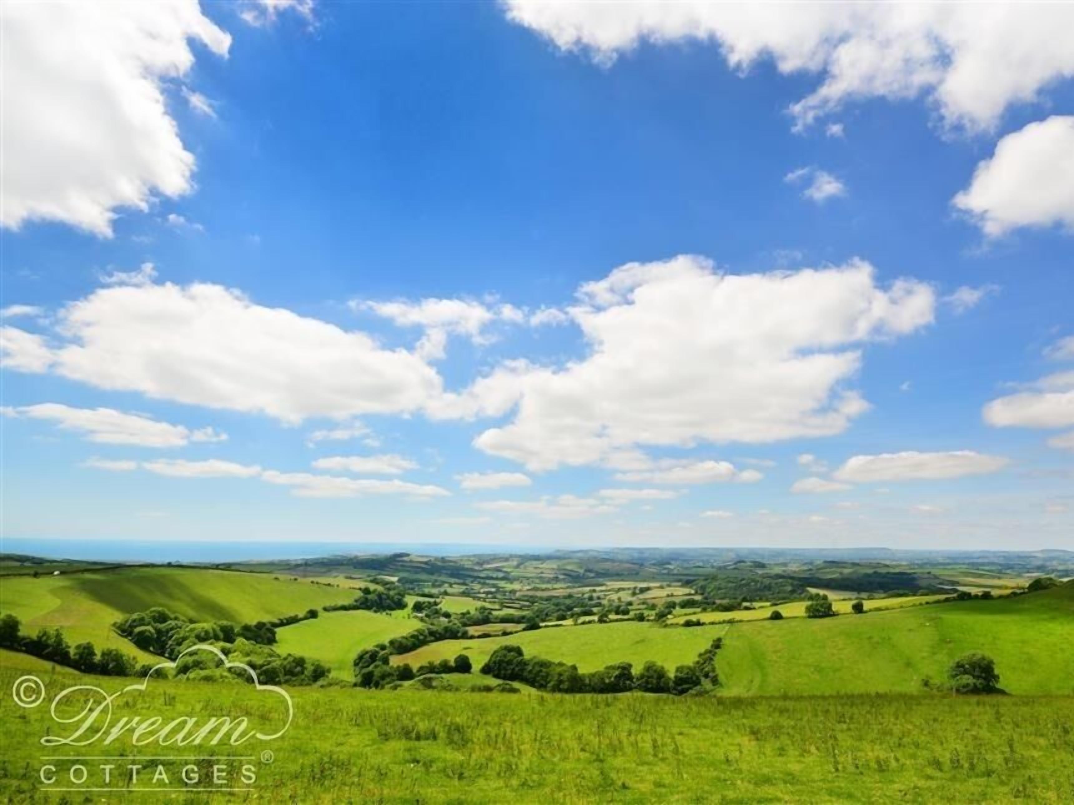 A landscape with rolling green hills and a clear blue sky.