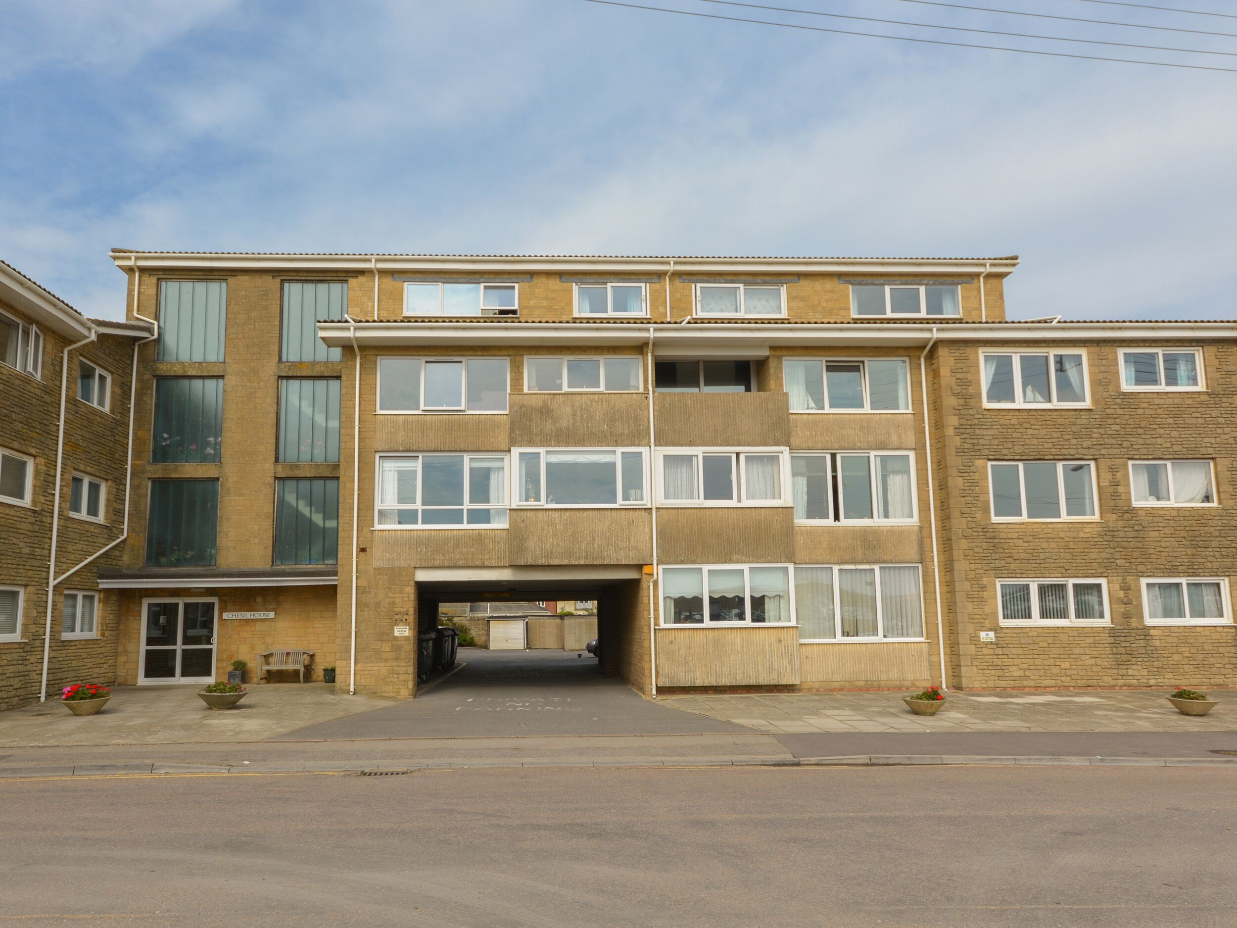 A multi-story building with a central entrance, large windows, and a brick facade.