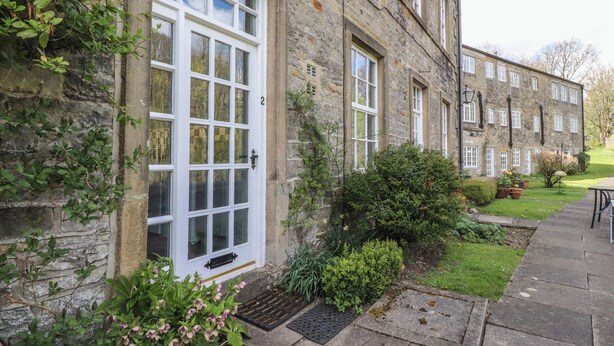 A stone building with a large white door and multiple windows. - 2 Riverside Walk (Skipton)