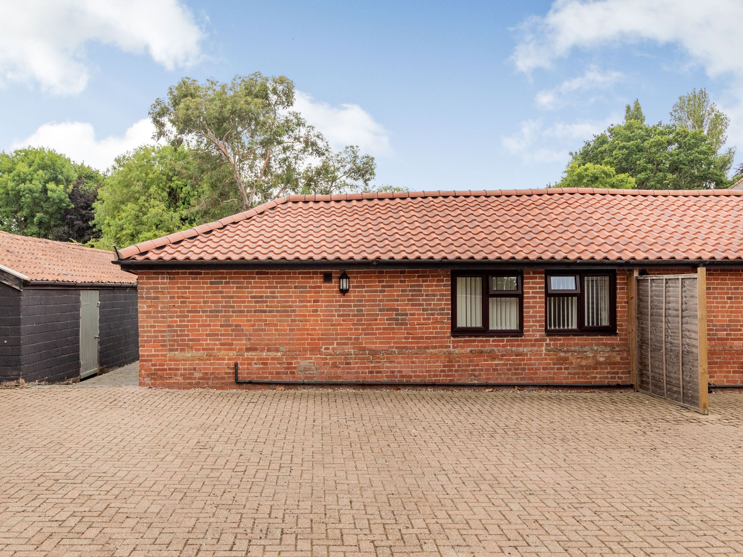A brick building with a tiled roof, a small window with a shutter, and a wooden door.