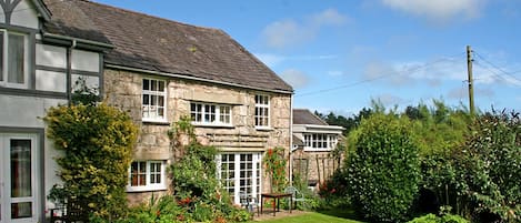 A stone house with a well-maintained lawn and garden.