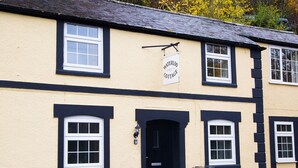 A building with a sign reading "Waterloo Cottage." It features a black door, white-framed windows, and a black and white exterior. - Hafan (Llangollen)