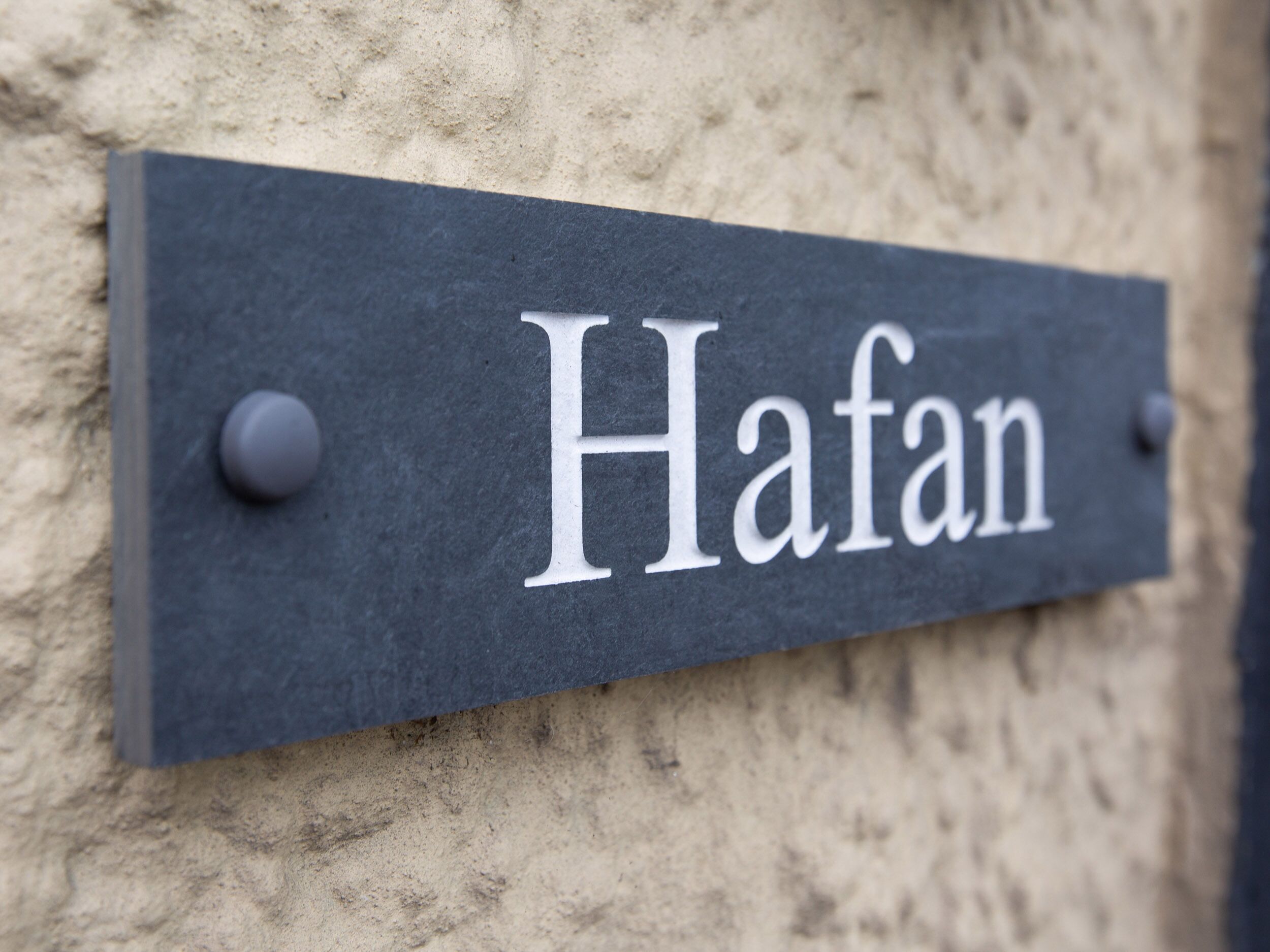 A slate nameplate with the name "Hafan" mounted on a textured wall.