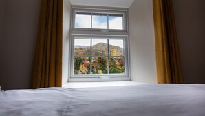 A bedroom with a large window overlooking a hilly landscape. - Hafan (Llangollen)