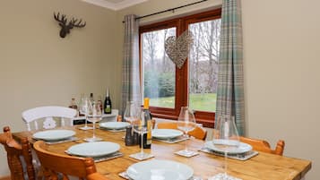 Mesa de comedor dispuesta para seis personas, con platos blancos, copas de vino y botellas.