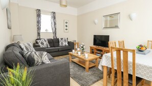 En moderne stue med sofa, sofabord, fjernsyn og spiseplads.