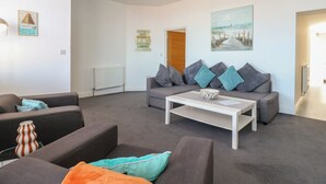 Uma sala moderna com um conjunto de sofás, uma mesa de centro e um quadro na parede.
