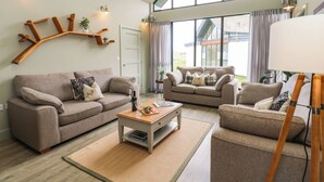 A modern living room with two sofas, a coffee table, and a decorative antler chandelier. - Restharrow Lodge (Bamburgh)