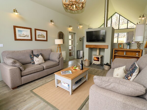 A cozy living room with a sofa, armchair, and a fireplace.