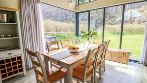 A dining area with a wooden table, chairs, and a bowl of fruit. - Restharrow Lodge (Bamburgh)