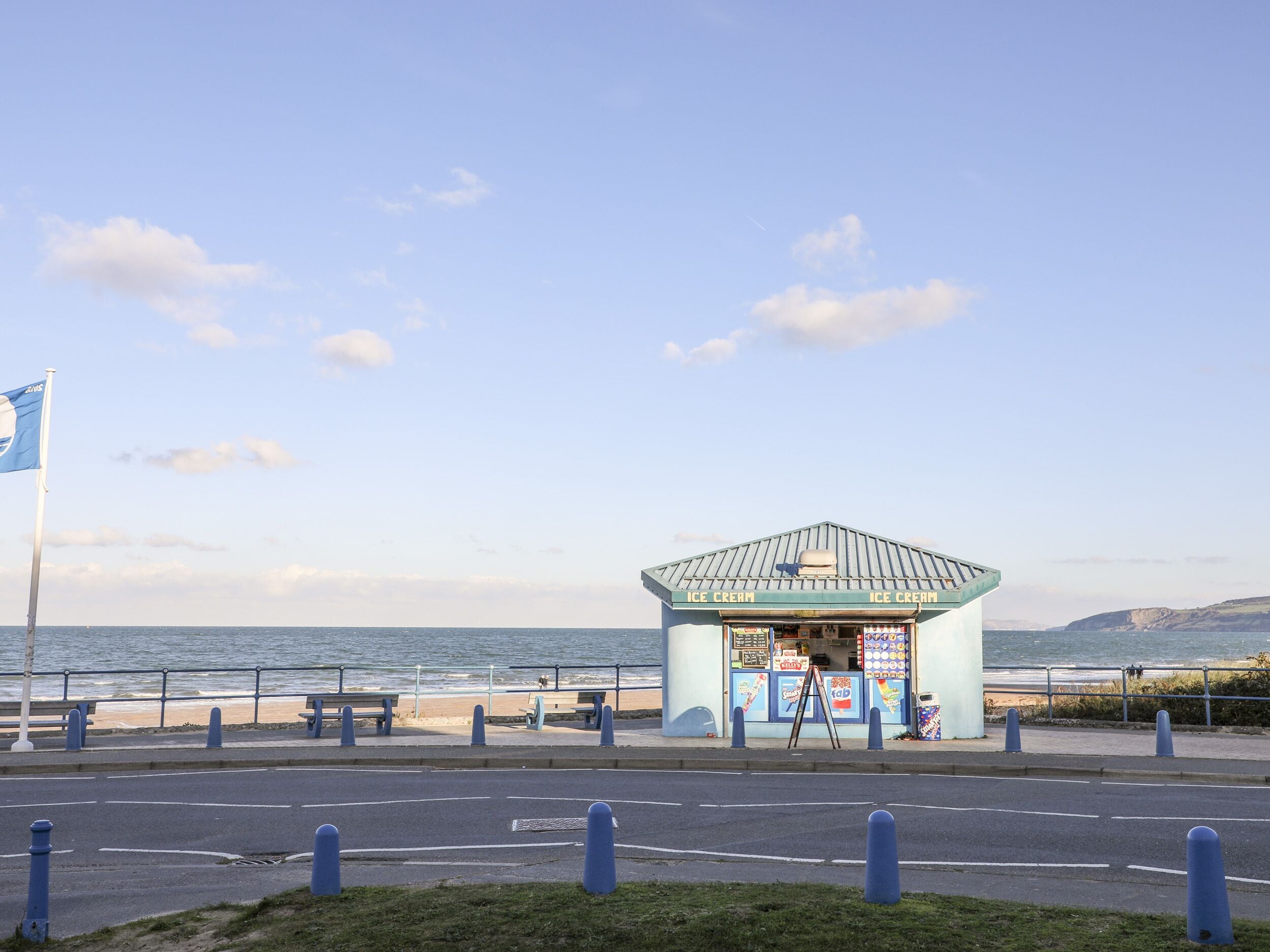 A small ice cream kiosk by the seaside with a clear view of the ocean.