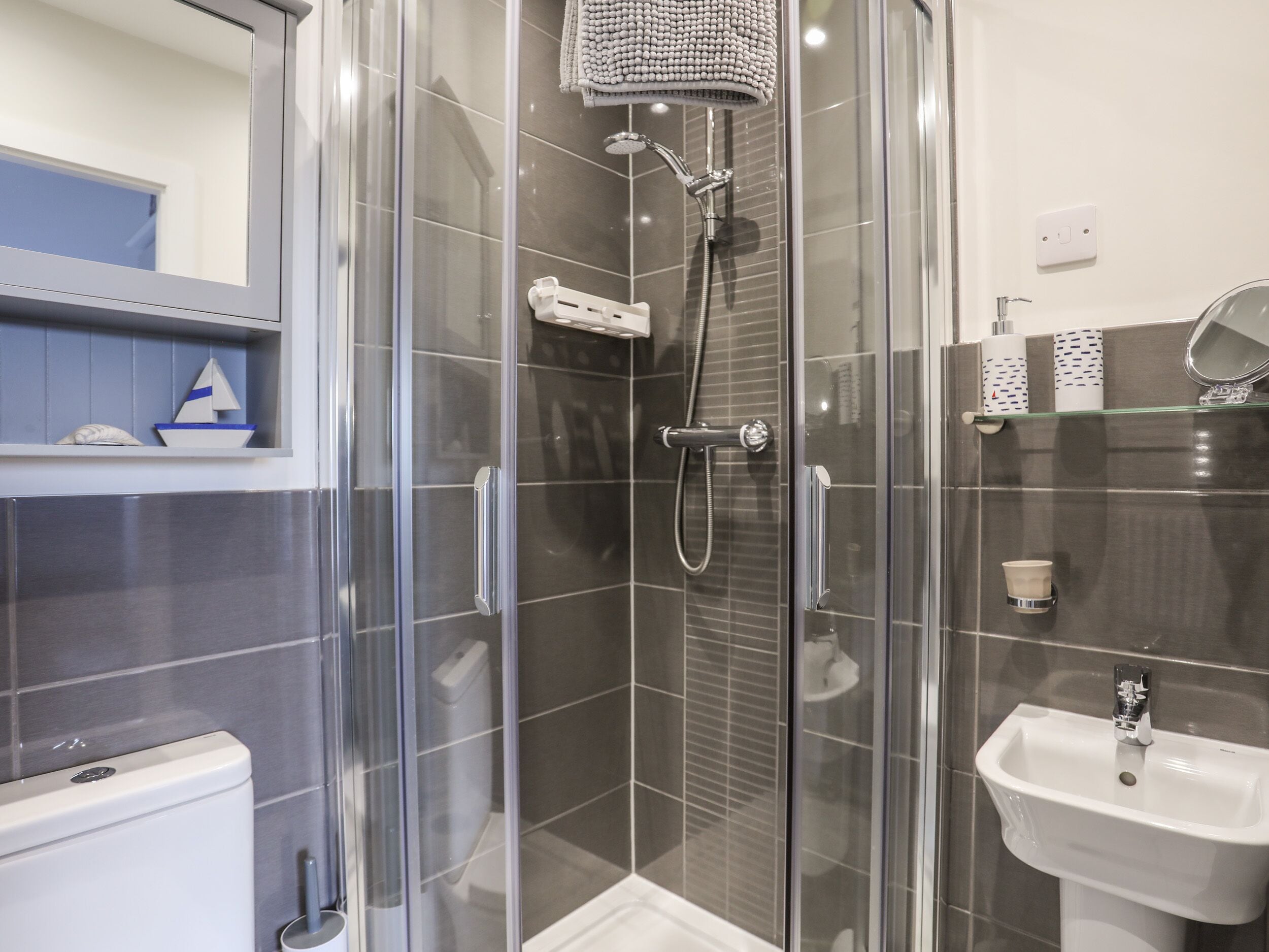 A modern bathroom with a glass-enclosed shower, a white sink, and a toilet.