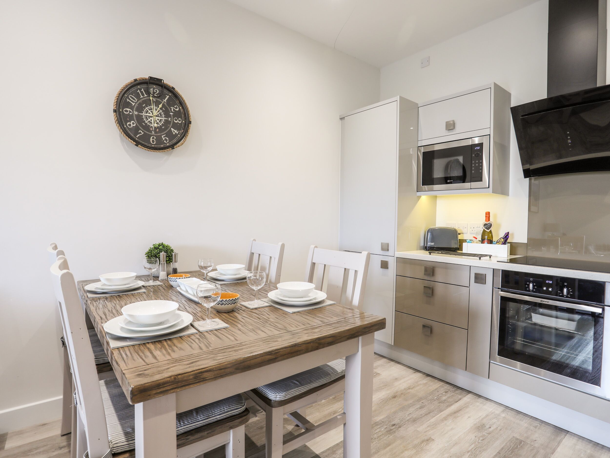 Una cucina moderna con mobili bianchi, forno integrato e microonde.