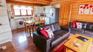 Un intérieur de chalet chaleureux comprenant un coin repas, un salon avec des canapés en cuir et une cuisine.