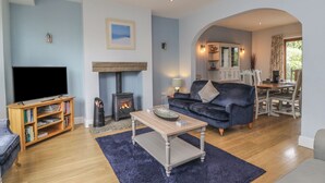 Una sala de estar con chimenea, televisor, sofá y comedor.