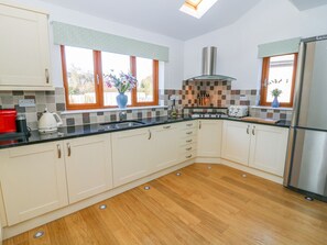 A modern kitchen with a central island, a built-in oven, and a stainless steel refrigerator. - Langtree (Carnforth)