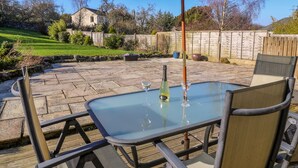 A patio with a glass table, chairs, and a green umbrella.
