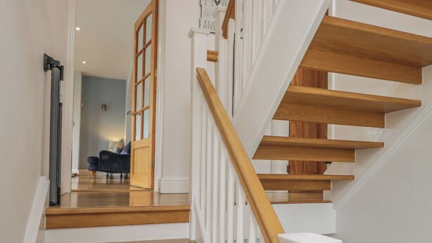 Una escalera con escalones de madera y barandillas blancas que lleva a una habitación con un sofá azul.