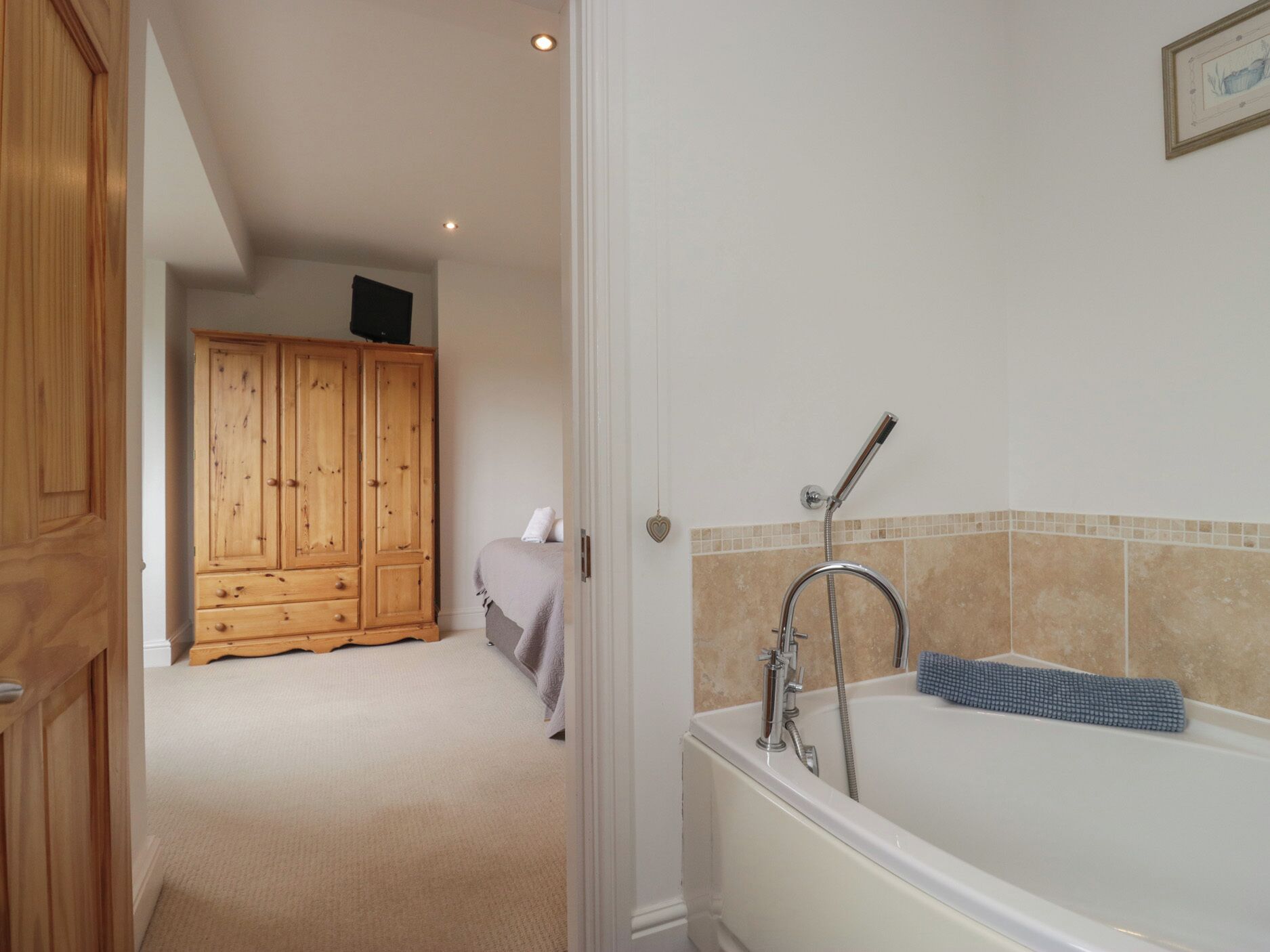 Een badkamer met een bad, een douche en een houten garderobe.